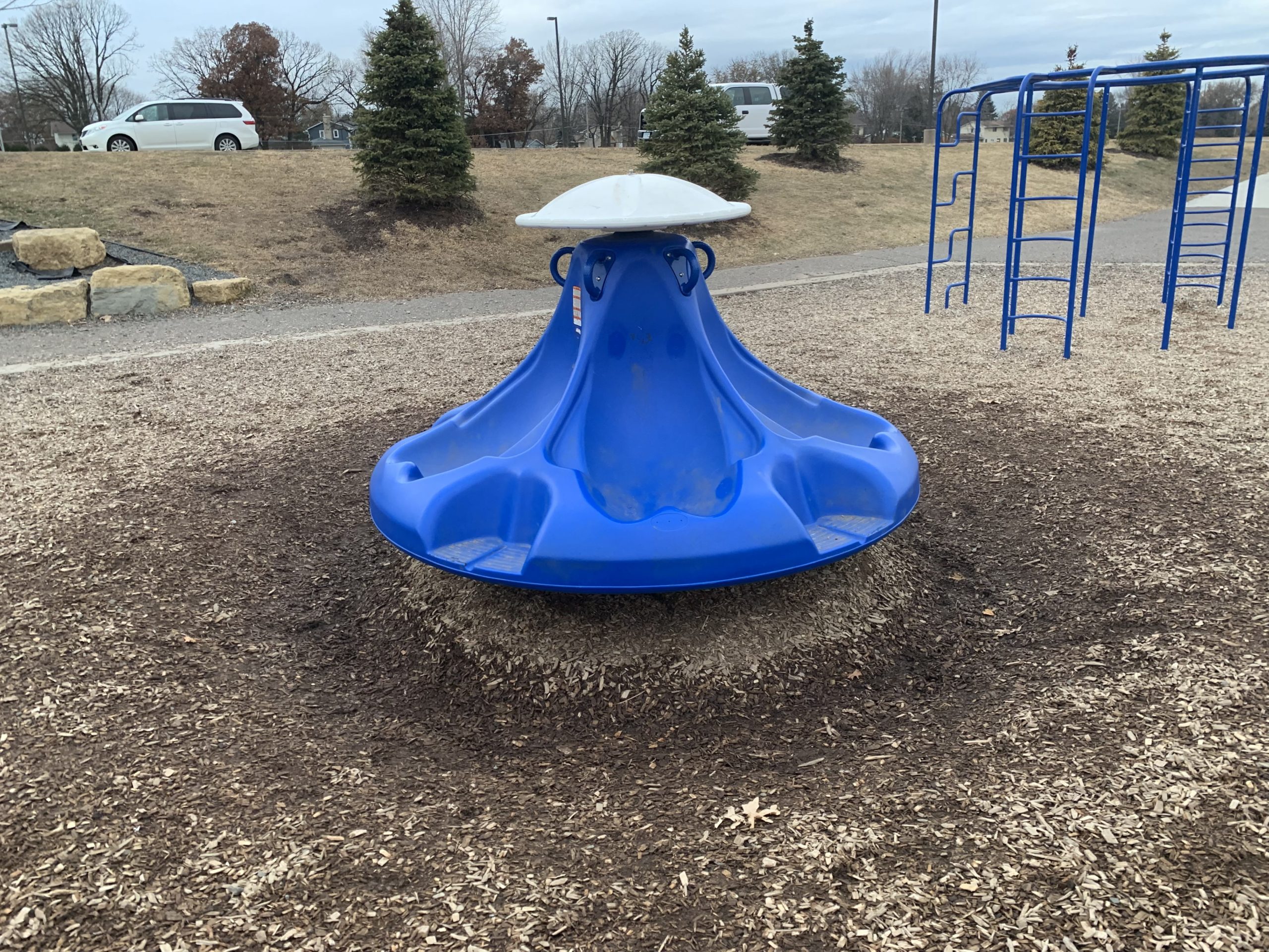 Playground spinner with large holes around it where the kids are running